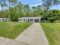 Charming single-story home featuring a gray exterior, attached garage, and long concrete driveway at 14837 Sussex Dr, Orlando, FL 32826