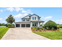 Beautiful home with a well-manicured lawn, mature trees, a three-car garage, and a welcoming front porch at 15208 Lake Claire Overlook Dr, Winter Garden, FL 34787