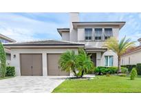 Beautiful home featuring a two-car garage, manicured lawn, and lush tropical landscaping at 15947 Vetta Dr, Bella Collina, FL 34756