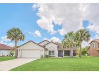 Charming single-Gathering home featuring a well-manicured lawn, palm trees, and a two-car garage at 2445 Ravendale Ct, Kissimmee, FL 34758