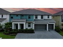 Beautiful two-story home featuring a three-car garage, manicured lawn, and a combination of teal and gray accents at 3880 Sonoma Blvd, Kissimmee, FL 34741