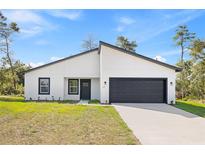 Charming single-story home featuring a modern white facade, black trim, and an attached two-car garage at 501 Marion Oaks Golf Way, Ocala, FL 34473