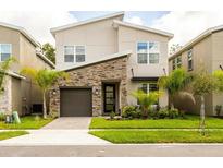 Modern two-story home showcasing a stone accent wall, well-maintained landscaping, and a single-car garage at 671 Drop Shot Dr, Davenport, FL 33896