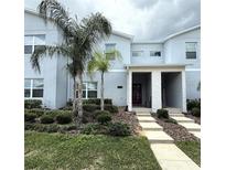 Stylish townhome with a modern exterior, landscaped front yard, and a striking red front door at 1078 Splash Shot Pl, Davenport, FL 33896