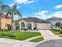 Charming single-story home with a manicured lawn, palm tree, and a welcoming front porch with decorative columns at 14036 Cherry Bush Ct, Orlando, FL 32828