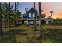Stunning blue home featuring a manicured lawn, wraparound porch, and double-door entry at 14205 Conifer Dr, Orlando, FL 32832