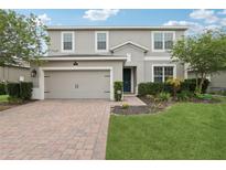 Charming two-story home with a brick driveway, manicured lawn and beautiful landscaping at 1450 Chelsea Manor Cir, Deland, FL 32724