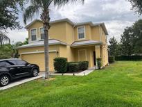 Two-story home with a well-maintained lawn, attached garage, and a black SUV parked in the driveway at 17614 Woodcrest Way, Clermont, FL 34714