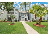 Charming two-story condo with light-blue siding, a well-manicured lawn, and mature trees creating a serene outdoor space at 2020 Royal Bay Blvd # 91, Kissimmee, FL 34746