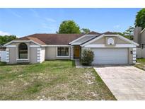 Charming one-story home with a well-manicured lawn, two car garage, and welcoming yellow front door at 7974 Village Green Rd, Orlando, FL 32818