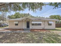 Charming single-story home with awnings, neutral paint, and a well-maintained front yard at 811 S Lone Oak Dr, Leesburg, FL 34748