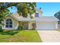 Charming yellow two-story home featuring a well-maintained front yard, arched window, and a two-car garage at 879 Matt Ln, Port Orange, FL 32127