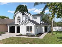 Charming two-story home features a black roof, white siding, black garage doors and manicured lawn at 9987 Triple Crown Cir, Orlando, FL 32825