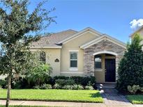 Charming single-story home boasts a stone facade, well-manicured lawn, and lush landscaping at 10126 Beach Port Dr, Winter Garden, FL 34787