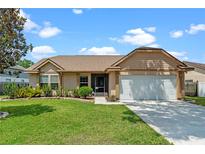 Charming single-story home featuring a well-manicured lawn, inviting front entrance, and two car garage at 10143 Pink Carnation Ct, Orlando, FL 32825