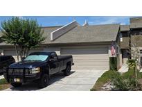 Charming townhome featuring a one-car garage, manicured lawn, and patriotic American flag display at 136 Teriwood Ct, Fern Park, FL 32730