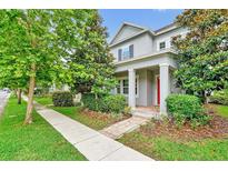 Charming two-story home featuring lush landscaping, inviting porch and red front door at 14208 Shocklach Dr, Winter Garden, FL 34787