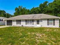 Charming single-story home with white brick exterior, dark shutters, well-manicured lawn, and attached garage at 3104 Lime Tree Dr, Edgewater, FL 32141