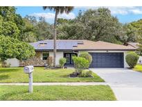 Charming single-story home featuring solar panels, a two-car garage, stone accents, and a well-manicured lawn at 322 Shadow Oak Dr, Casselberry, FL 32707