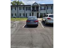 Two-story condo building featuring stairs to upper units, parking spaces, and neutral-toned exterior at 7628 Forest City Rd # 054A/K/A F, Orlando, FL 32810