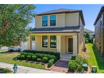 Charming two-story home with a well-manicured lawn, colorful bushes, and a lovely front porch at 8057 John Hancock Dr, Winter Garden, FL 34787