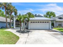 Charming single-Gathering home featuring a metal roof, a two-car garage and lush tropical landscaping at 2391 Piedmont Lakes Blvd, Apopka, FL 32703