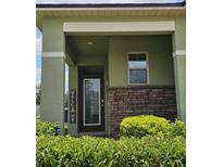 Inviting front entry with decorative glass door, stone accents, and lush landscaping at 3371 Yellowtop Loop, Clermont, FL 34714