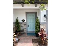 Charming facade featuring a light blue front door, brick accents, and decorative plants, creating a welcoming entrance at 391 Cape Honeysuckle Pl, Sanford, FL 32771