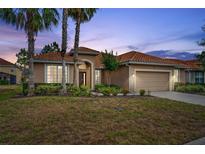 Charming single-story home featuring a tile roof, front-facing garage, and tropical landscaping at 4080 Oaktree Dr, Davenport, FL 33837