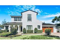Stunning two-story white home featuring arched entry, front balcony, well-manicured landscaping and a wood-look garage door at 521 S Phelps Ave, Winter Park, FL 32789