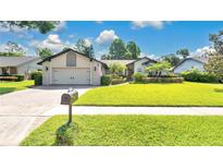Charming home featuring a lush lawn, mature landscaping, and a brick driveway at 623 Tuskawilla Point Ln, Winter Springs, FL 32708