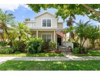 Charming two-story home with a lush garden, an American flag, and a welcoming front porch at 7003 Cupseed Ln, Harmony, FL 34773