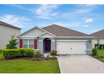 Charming single-story home with a well-manicured lawn, a two-car garage and red shutters at 868 Brooklet Dr, Davenport, FL 33837