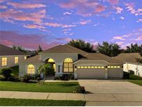 Charming single-story home with manicured lawn, three-car garage, and beautiful landscaping at dusk at 10955 Lemay Dr, Clermont, FL 34711
