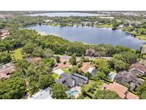 Stunning aerial view of lakeside home, lush greenery, and inviting pool, making it perfect for relaxation at 1327 Bridgeport Dr, Winter Park, FL 32789