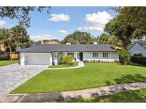 Charming exterior with lush green lawn, brick driveway, and meticulous landscaping at 1327 Bridgeport Dr, Winter Park, FL 32789
