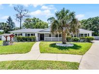 Charming white brick home featuring a well-manicured lawn, inviting walkway, and mature landscaping at 174 Pine Grove Ct, Daytona Beach, FL 32119