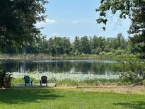 Scenic waterfront view with Adirondack chairs on a dock, offering serene relaxation and beautiful nature at 2028 Lake Christie Dr, Orlando, FL 32809