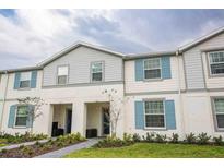 Inviting two-story townhome showcasing a charming exterior with light blue shutters and manicured landscaping at 271 Jetty Way, Davenport, FL 33897