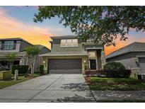 Beautiful two-story home with a well-manicured lawn and inviting two-car garage at sunset at 2850 Pewter Mist Ct, Oviedo, FL 32765