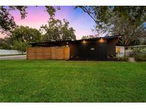 Modern home featuring a lush green lawn, minimalist landscaping, and a unique covered carport area at 4201 Mizell St, Orlando, FL 32812
