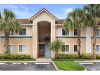 Inviting condo exterior showcasing lush landscaping, palm trees, and well-maintained facade at 527 Villa Del Sol Cir # 104, Orlando, FL 32824