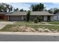 A single-story home with an attached garage and neutral-colored exterior sits on a grassy lot at 5918 Stratton Ln, Orlando, FL 32808