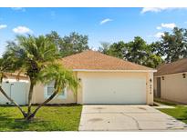 Charming single-story home featuring a two-car garage, well-maintained lawn, and a young palm tree at 6819 Belmar Dr, Orlando, FL 32807