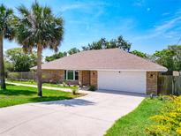 Charming brick home with a manicured lawn, mature palm trees, and a two-car garage at 1233 Gladstone Dr, Deltona, FL 32725