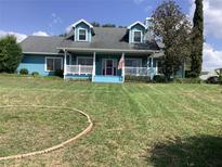 Charming blue home with a well-manicured lawn, white porch, and patriotic American flag at 13111 Sunshine Cir, Clermont, FL 34711