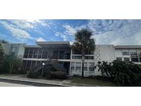 Condo building with screen porches, stairs and mature landscaping under blue skies at 151 N Orlando Ave # 118, Winter Park, FL 32789