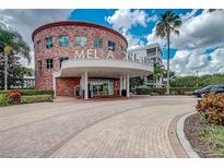 The building entrance features a brick facade, covered entrance and circular driveway surrounded by manicured greenery and palm trees at 225 Celebration Pl # 527, Kissimmee, FL 34747