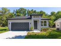 Beautiful single-story home featuring a gray exterior, dark gray garage door, and neatly landscaped front yard at 25 W 7Th St, Apopka, FL 32703
