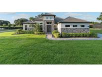 Charming single-Gathering home featuring stone accents, a well-manicured lawn, and a tiled roof at 25859 Crossings Bluff Ln, Sorrento, FL 32776